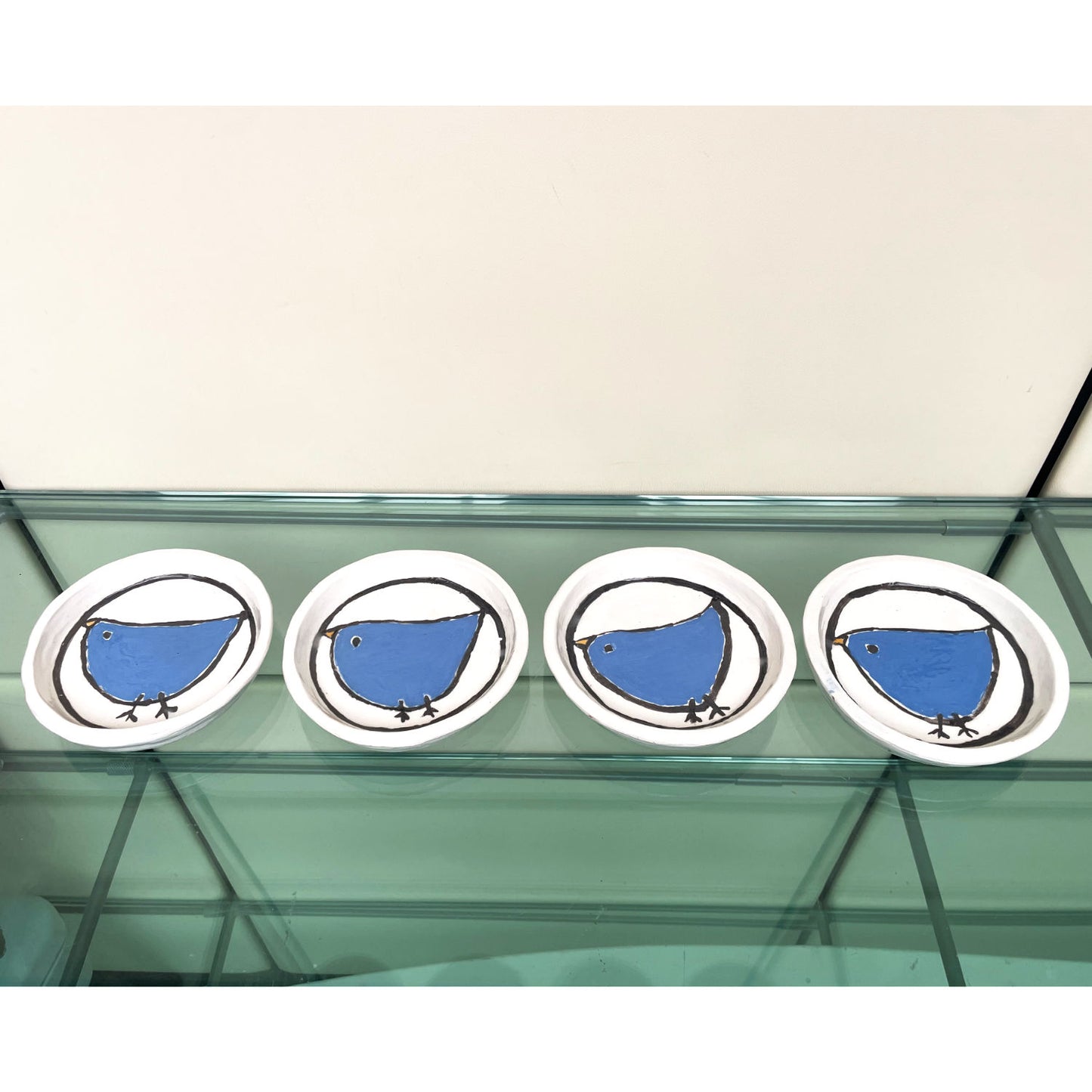 Handgemaakte witte keramische bordjes met een blauw vogeltje in volkskunststijl, set van 4