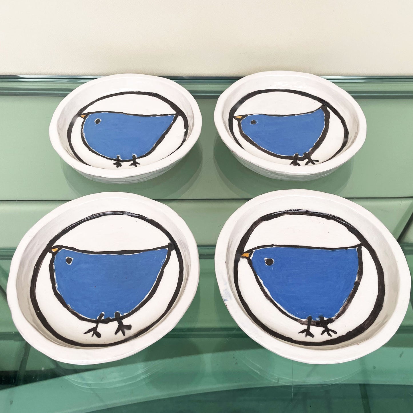 Handgemaakte witte keramische bordjes met een blauw vogeltje in volkskunststijl, set van 4