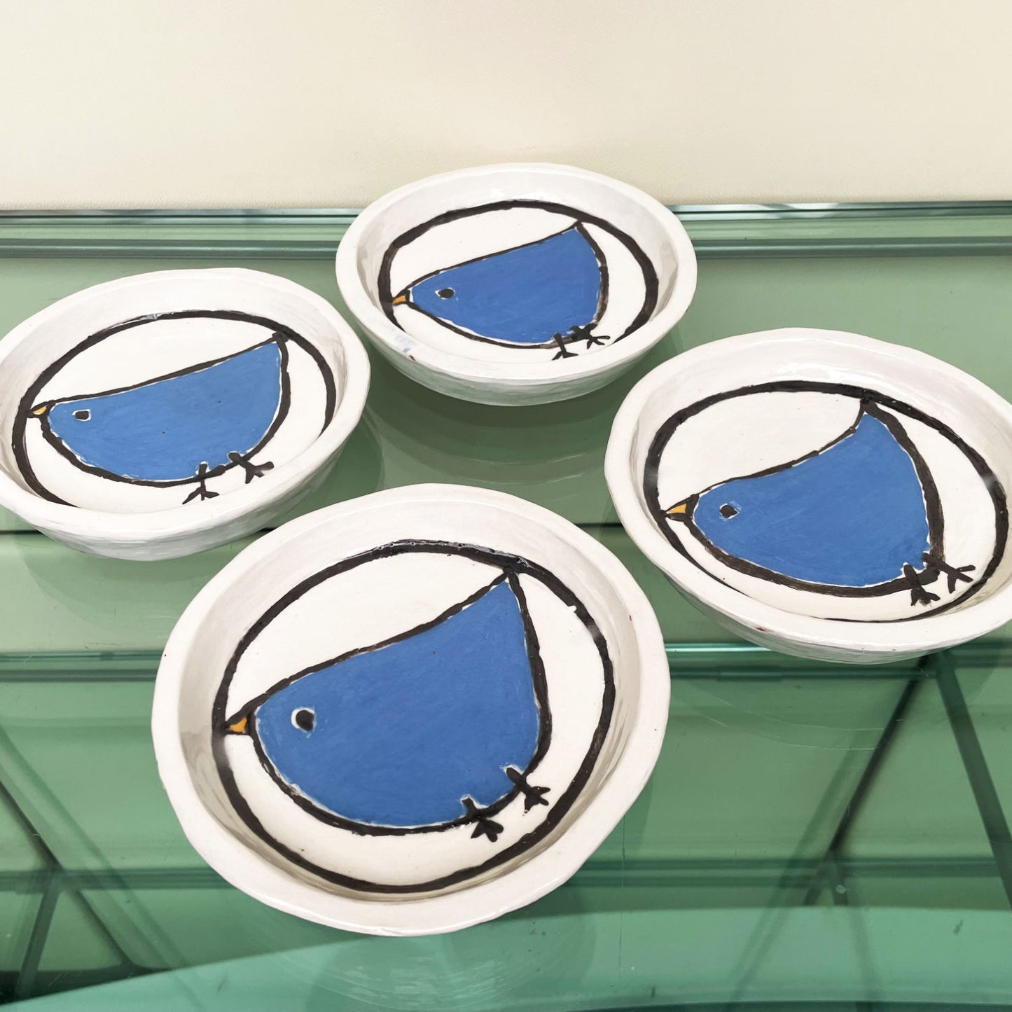 Handgemaakte witte keramische bordjes met een blauw vogeltje in volkskunststijl, set van 4
