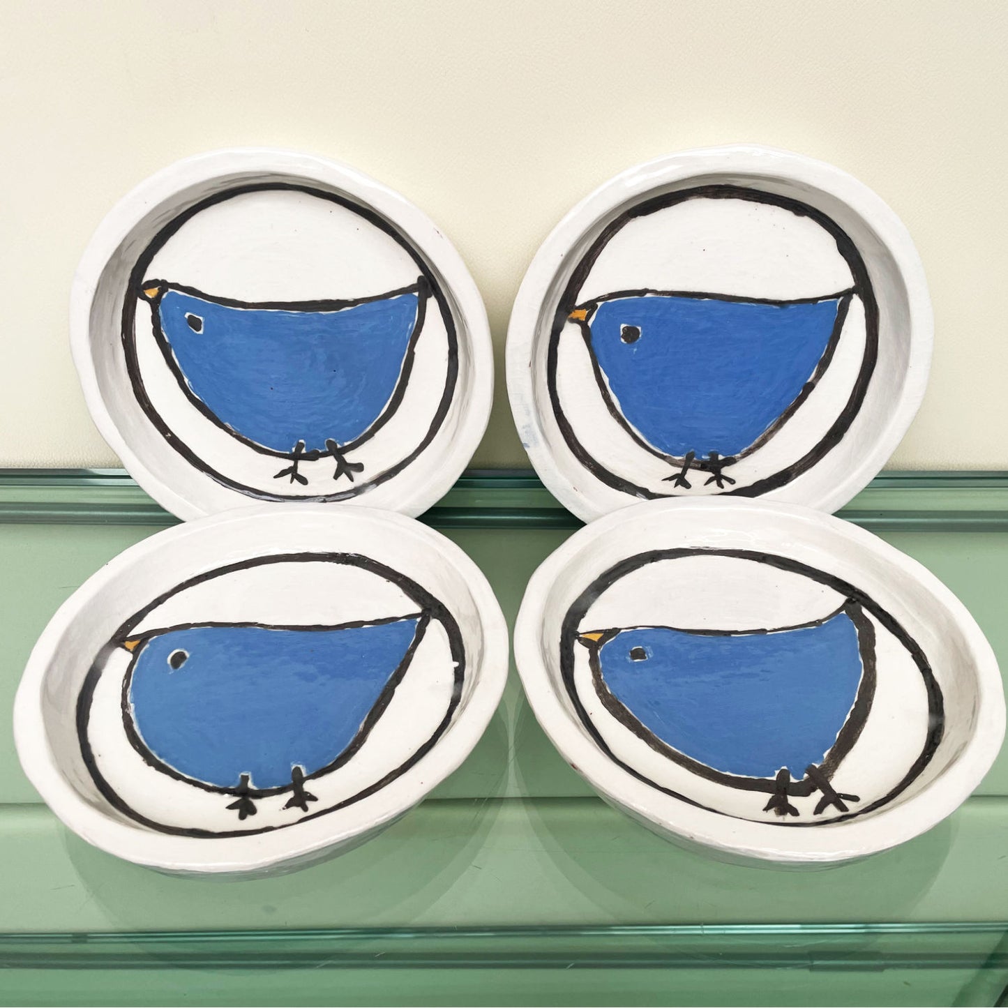 Handgemaakte witte keramische bordjes met een blauw vogeltje in volkskunststijl, set van 4